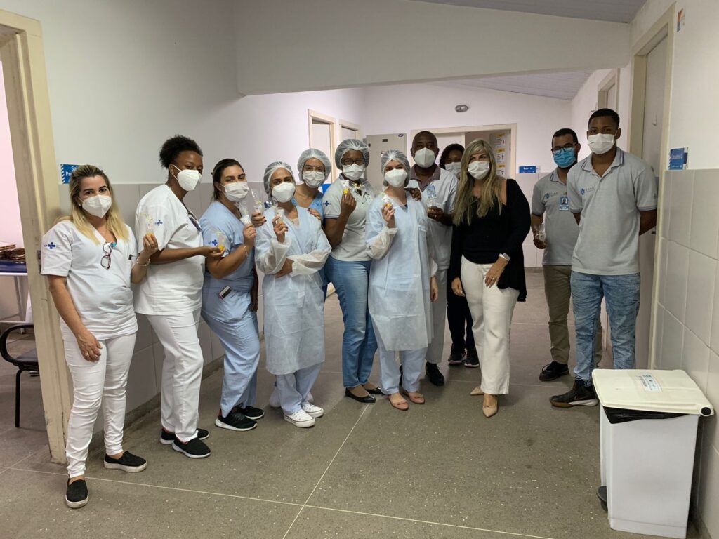 Várias pessoas posam para foto uma ao lado da outra num corredor da unidade de saúde.