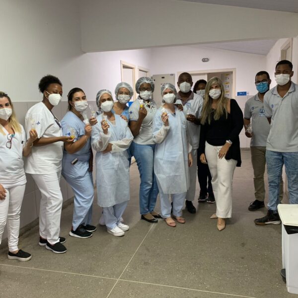 Várias pessoas posam para foto uma ao lado da outra num corredor da unidade de saúde.